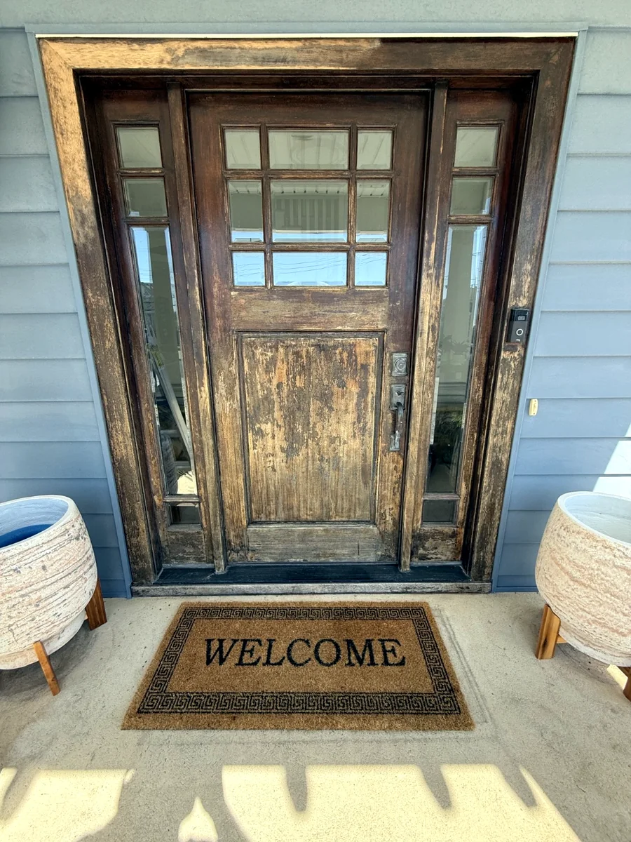 Weathered natural wood front door before restoration